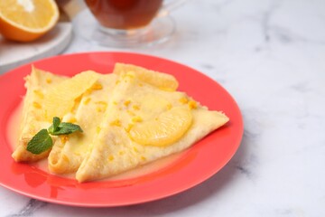 Plate with tasty crepes Suzette on white marble table, closeup. Space for text