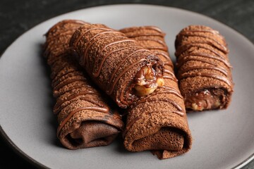 Delicious chocolate crepes with sweet paste and nuts on table, closeup