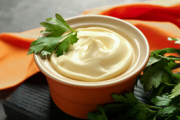 Delicious mayonnaise sauce in bowl with parsley on table, closeup