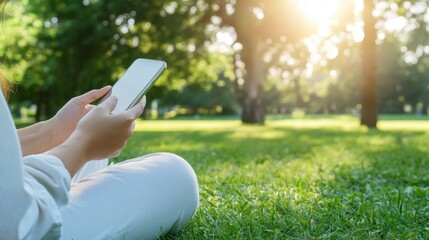 Moment of Connection: A woman sits on a vibrant green lawn, surrounded by the tranquil beauty of a summery park. The golden sunlight filters through the trees as she gently scrolls on her phone.