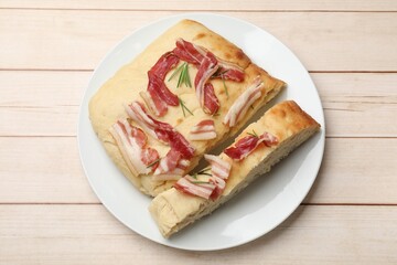 Pieces of delicious focaccia bread with bacon and rosemary on wooden table, top view