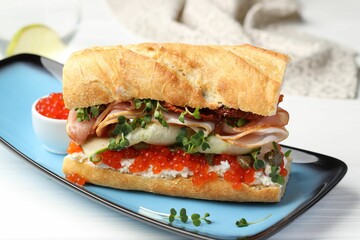 Delicious baguette sandwich with caviar, ham and capers on white wooden table, closeup