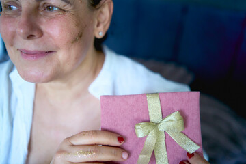 a senior woman in underwear with gold glitter on her face and hands holding a gift certificate