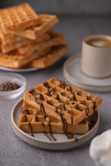 photo Delicious homemade waffles with chocolate drizzle served with coffee, offering a delightful breakfast experience perfect for brunch, dessert, or an indulgent morning treat.