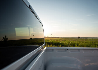 Pickup truck rear window. Looking at the green meadow in the background from the cargo bed of white pickup truck. © andrbk