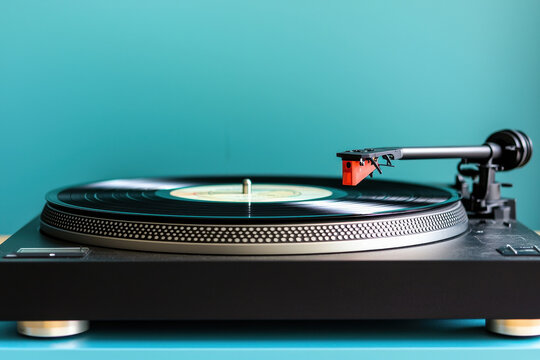 Vintage vinyl record player with black turntable on turquoise background.