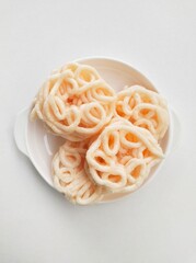 Palembang fish crackers in a white plate on a white background. Top of view. 