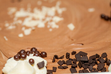A closeup view of a rich and decadent chocolate dessert generously topped with creamy frosting and chocolate sprinkles