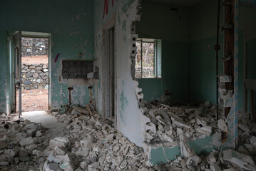 Demolished room with rubble and open door revealing stone wall