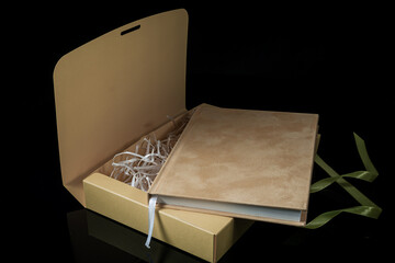 Best gift for men. Man gift concept. Yellow notebook with yellow gift box on black background. Copy space. Valentine's day, wedding, birthday and special occasion gift concept. Copy space for text.