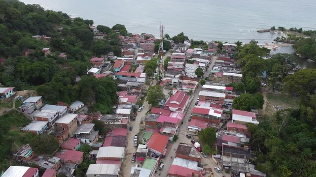 Aerial view of Chuspa, Venezuela &ndash; Coastal fishing village surrounded by lush green mountains and tropical forest, beach shoreline and calm sea, beautiful natural landscape