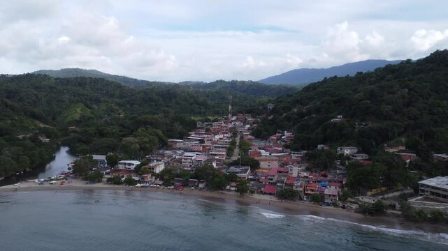 Aerial view of Chuspa, Venezuela &ndash; Coastal fishing village surrounded by lush green mountains and tropical forest, beach shoreline and calm sea, beautiful natural landscape