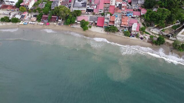 Aerial view from the beach of Chuspa, Venezuela &ndash; Coastal fishing village surrounded by lush green mountains and tropical forest, beach shoreline and calm sea, beautiful natural landscape