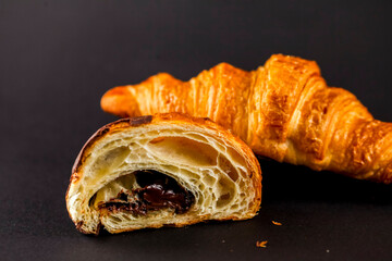 Freshly baked croissants and chocolate-filled pastry on dark surface