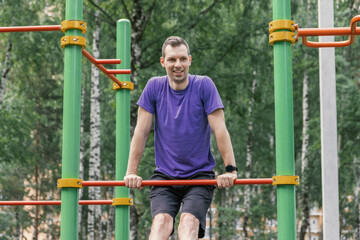 Man doing push-ups on low bar outdoors