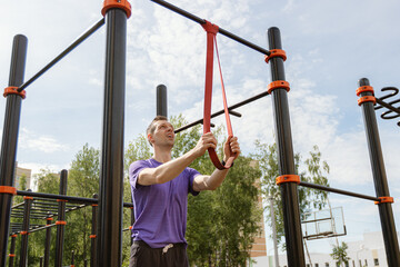 Focused man securing resistance bands at an outdoor workout ground