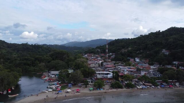 Aerial view of Chuspa, Venezuela &ndash; Coastal fishing village surrounded by lush green mountains and tropical forest, beach shoreline and calm sea, beautiful natural landscape