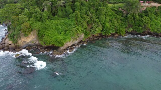 Aerial view of Chuspa, Venezuela &ndash; Coastal fishing village surrounded by lush green mountains and tropical forest, beach shoreline and calm sea, beautiful natural landscape