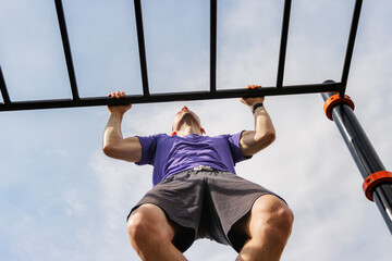 Pull-up on outdoor monkey bars under clear sky