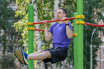 Athlete practicing leg-raise pull-up in sunny park setting