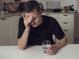 Man holding his head from a headache, a soluble pill in his other hand, preparing for relief.