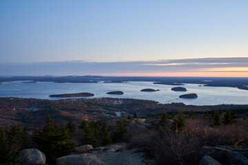 A sweeping view over Bar Harbor Maine from Cadillac Mountain in Acadia National Park. It is just before sunrise, and the sleepy little town begins to awake. The sky is mostly blue with some pink.