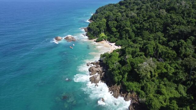 Aerial view of Mono Manso Beach, a secluded tropical paradise near Chuspa, Venezuela &ndash; Lush green forest, rocky shoreline, golden sand, and crystal-clear turquoise water