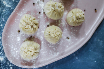 Top View of Homemade Dumplings with Flour and Peppercorns on a Pink Plate