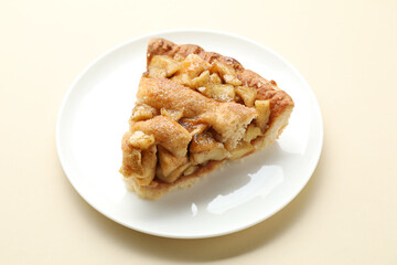Slice of homemade apple pie on beige background, closeup