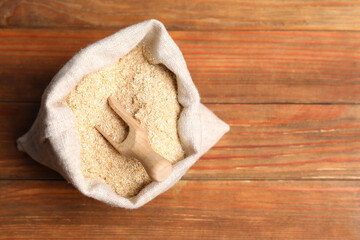 Oat bran and scoop in burlap bag on wooden table, top view. Space for text