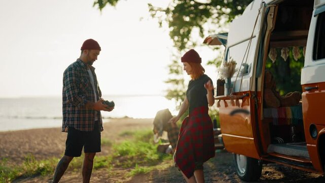 Trip to sea by camper, man and woman taking funny pictures in camp, lady dancing . Carefree young people traveling by motorhome, enjoying freedom and beautiful nature, slow motion, cute female posing