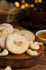 Tasty cashew cookies with powdered sugar on wooden table, closeup