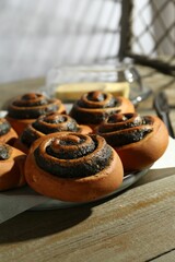 Tasty buns with poppy seeds on wooden table, closeup