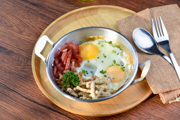 A photo of a plate of food that has two eggs, bacon, and other ingredients.