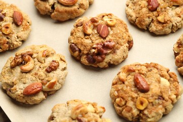 Tasty cookies with nuts on parchment paper, closeup