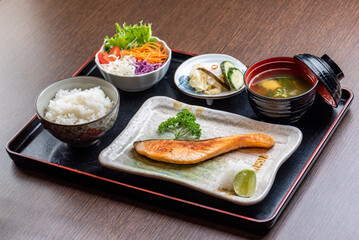 A delicious and healthy Japanese meal with grilled salmon, rice, salad, and miso soup.