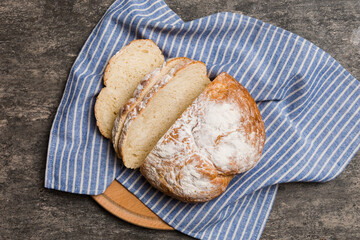 Freshly baked bread slices on cutting board against white wooden background. top view Sliced bread