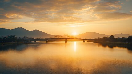 Naklejka premium Golden Sunset Over Bridge and Mountain River Scene
