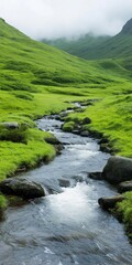 A river flows through a lush green valley. The water is crystal clear and the grass is vibrant green. The scene is peaceful and serene, with the sound of the water