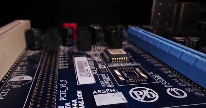 Computer motherboard elements macro in slow motion: RAM DDR DIMM memory, BIOS capacitors, resistors, microcircuits, plis, PCI, SATA on a black background close-up. Yellow, blue, black, white slot.