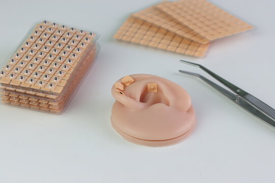 Auriculotherapy Seeds and a simulated ear in a light background to training the technique 