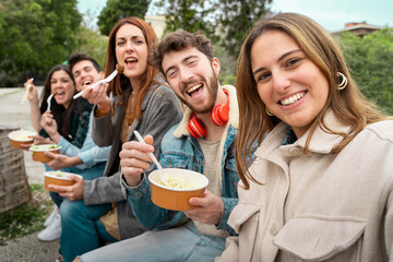 Group of friends smiling and enjoying plastic-free eco-friendly take-away meals outdoors