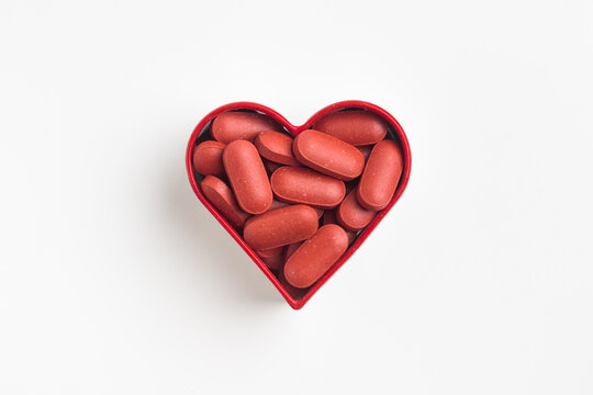 The heart made of red pills on a white background. Medicinal pills and capsules for health, dietary supplements and vitamin iron Fe for iron deficiency anemia prevention