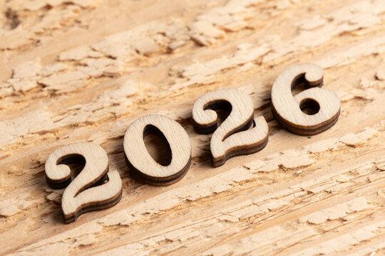 Wooden figures forming number 2026 on rustic wooden background.