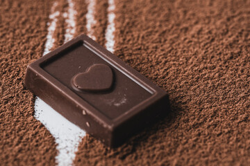 Chocolate bar with heart on cocoa powder sweet food and drink.
