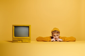 A fashionable young redhead rests his chin on his hands while dressed warmly in a trendy outfit.