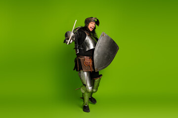 Medieval knight in metal armor with sword and shield on bright green background
