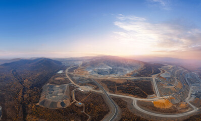 Aerial view of large open-pit mine at sunrise in mountainous landscape