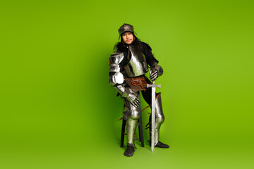 Medieval Knight in Armor Holding a Sword on a Green Background