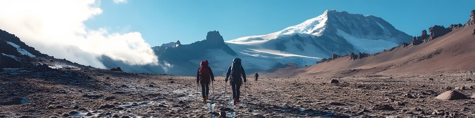 Fototapeta premium Wide shot of climbers crossing the alpine desert zone on the way to the summit, with Kilimanjaros glaciers shimmering in the distance, in 4K resolution